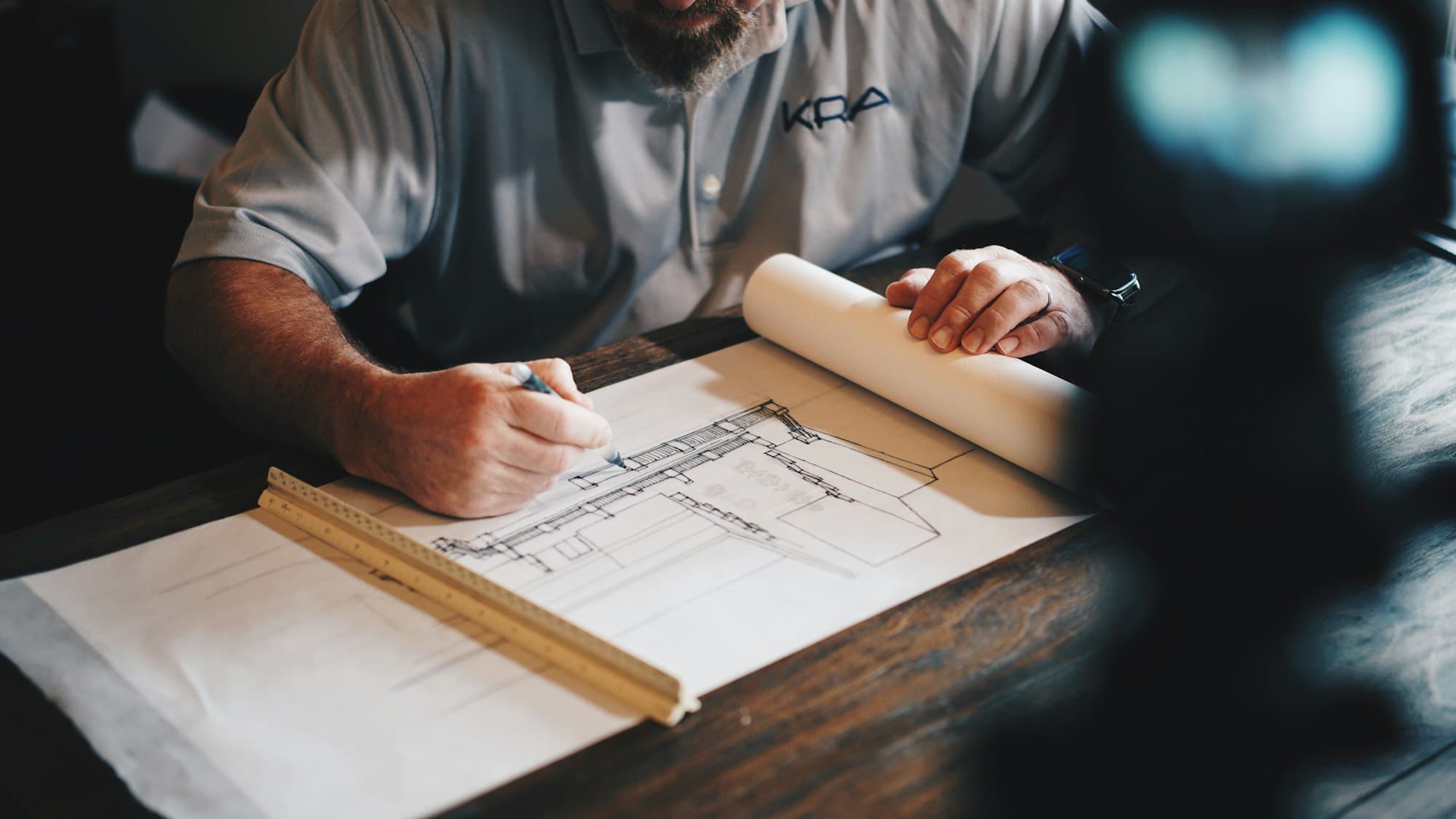 Engineer drafting technical blueprints at a worktable