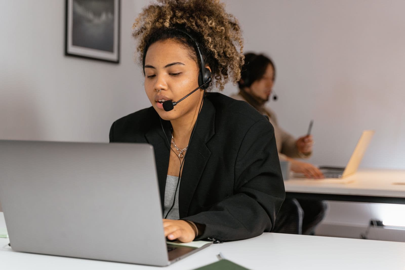 Call center agent wearing a headset working at her laptop in a bright office